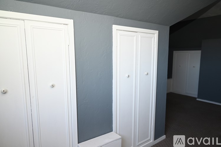 Three white doors in a room with grey walls.