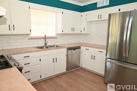 A kitchen with white cabinets and a stainless steel refrigerator.