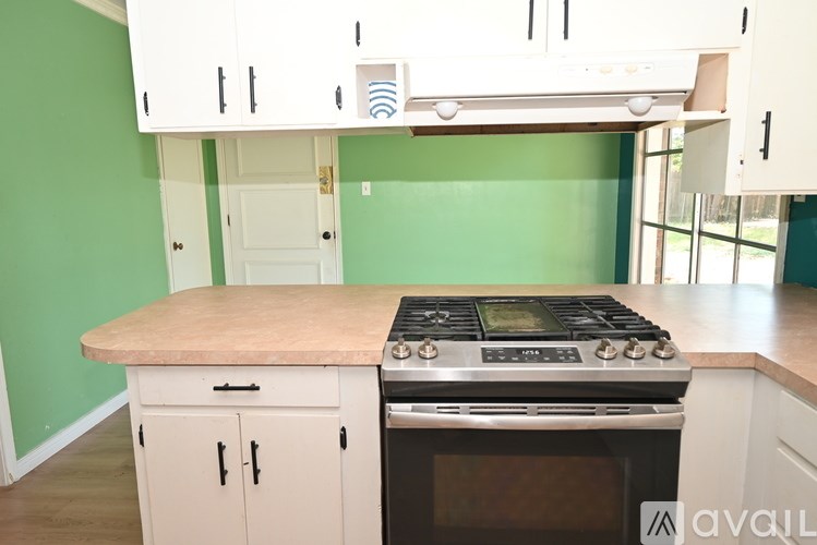 A kitchen with green walls and white cabinets.