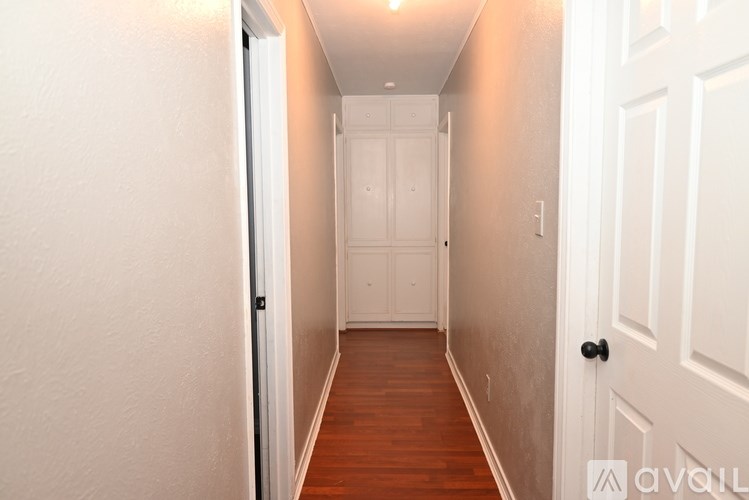 A hallway with a white door and a black handle.