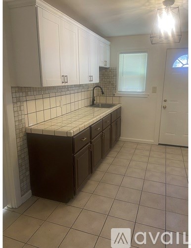 A kitchen with white cabinets and a tiled backsplash.