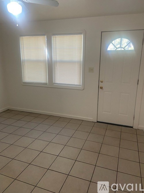 A room with a white door and two windows with blinds.