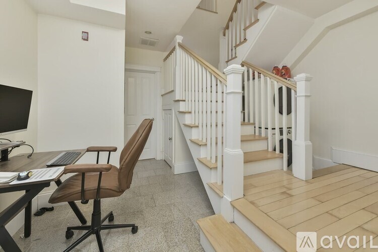 A room with a staircase and a desk with a computer.