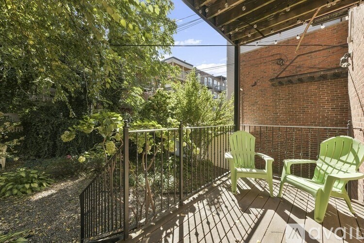 Two green chairs on a wooden deck with a metal railing.