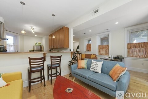 A living room with a blue couch and a red coffee table.