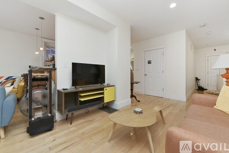 A living room with a television, a chair, a sofa, and a coffee table.