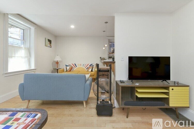 A living room with a blue couch, a television, and a yellow cabinet.