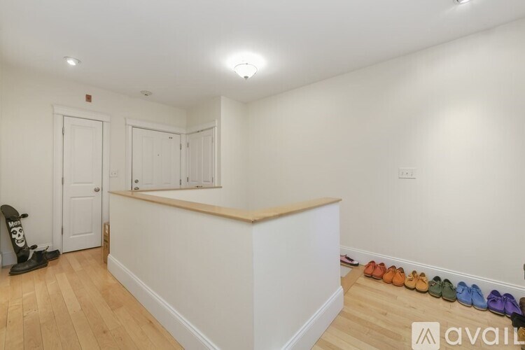 A room with a white wall and a row of shoes on the floor.