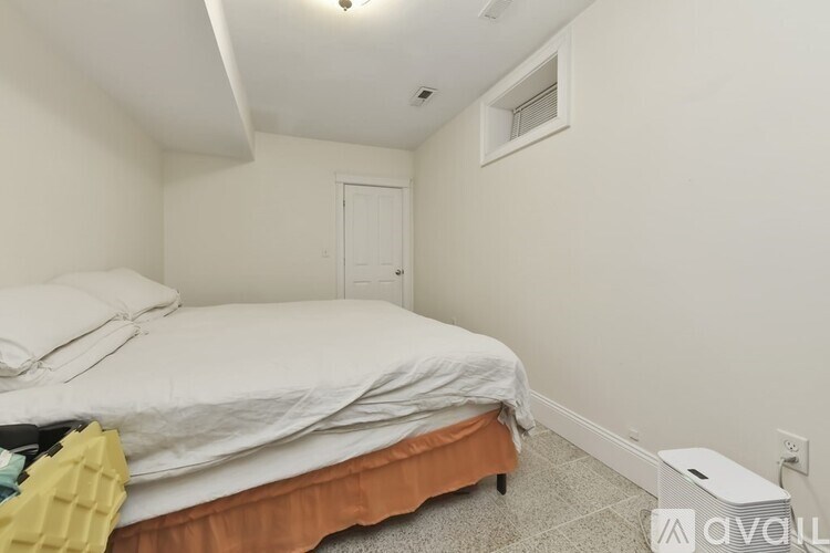 A bedroom with a bed, nightstand, and window.