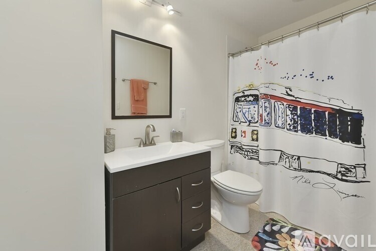 A bathroom with a toilet, sink, and a shower curtain with a train design on it.