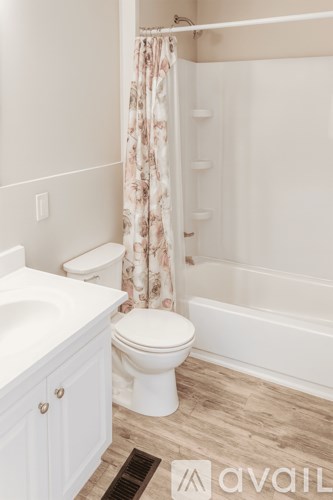 A white toilet in a bathroom with a wooden floor.