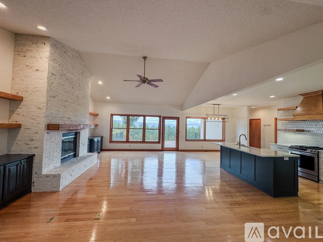 A spacious kitchen with a fireplace and wooden floors.