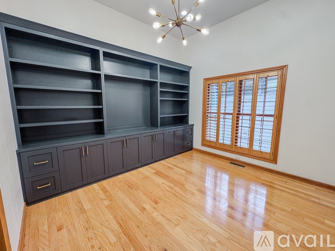 A room with a large shelving unit and a window with wooden shutters.