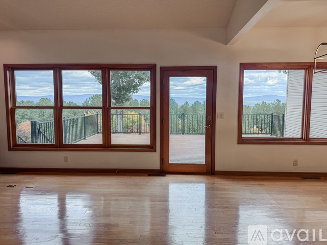 A room with wooden floors and a large window overlooking a fence.