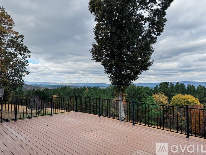 A deck with a railing overlooks a mountainous landscape.