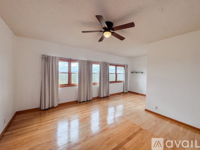 A room with a ceiling fan and wooden flooring.