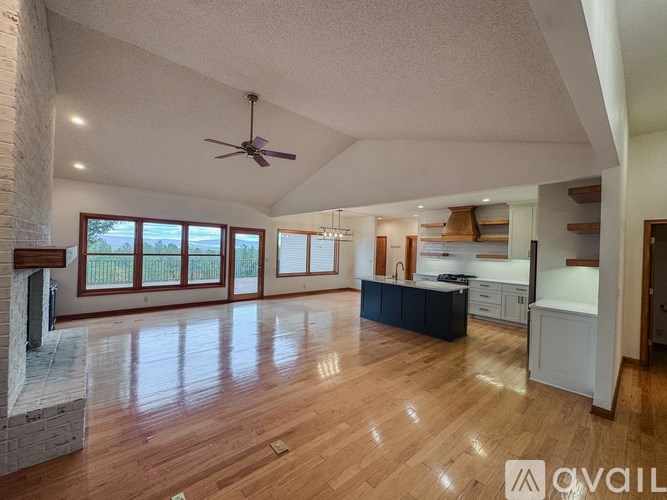 A spacious living room with a fireplace and a kitchen area in the background.