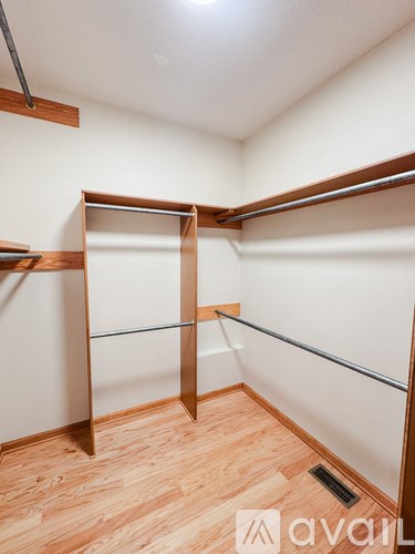 A room with a wooden floor and a wall-mounted clothes rack.