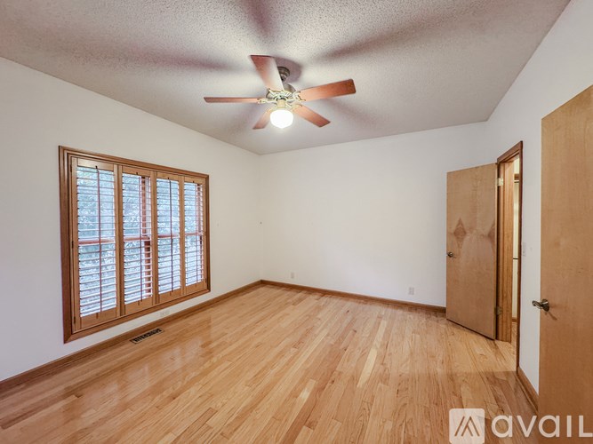 A room with a ceiling fan and wooden flooring.