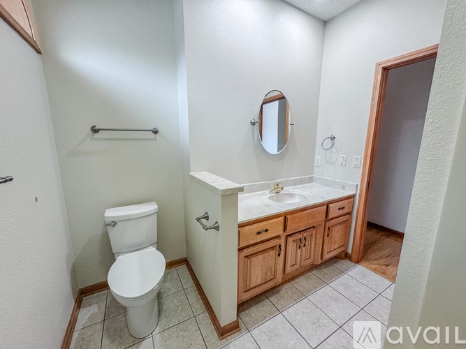 A bathroom with a toilet, sink, and mirror.
