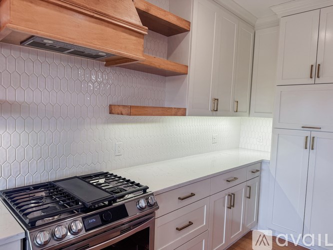 A kitchen with a stove top oven and white cabinets.