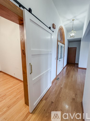 A hallway with a white door and wooden floors.