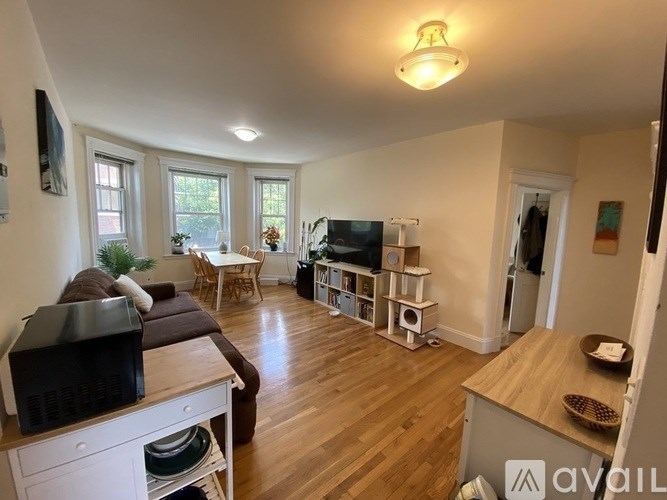 A living room with a brown couch and a television on a white cabinet.