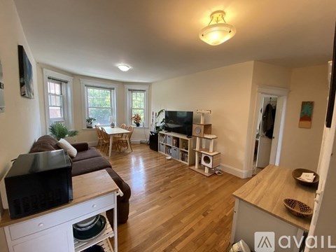 A living room with a brown couch and a television on a white cabinet.
