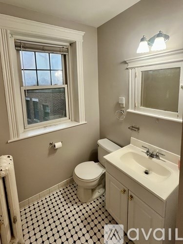 A bathroom with a toilet, sink, and window.