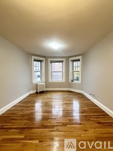 A room with wooden floors and two windows.