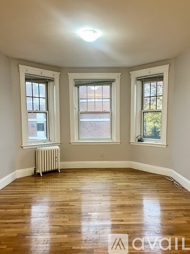 A room with wooden floors and three windows.
