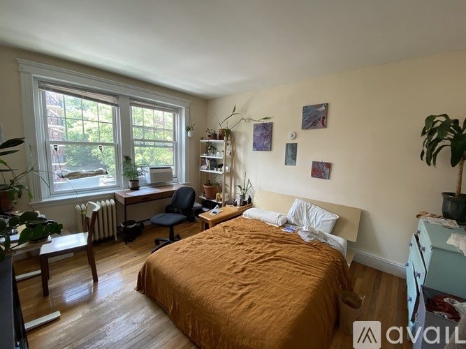 A bedroom with a bed, desk, chair, and window.