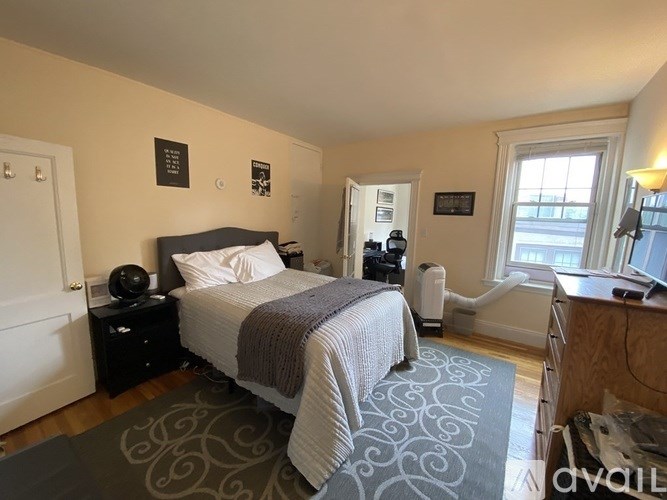 A bedroom with a bed, nightstand, and window.