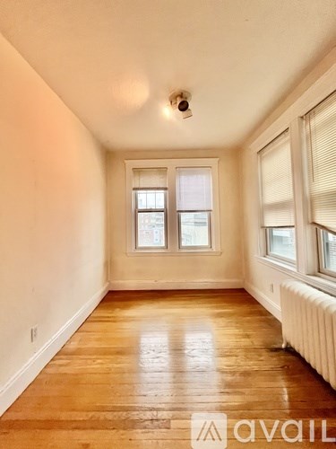 A room with wooden floors and a window with blinds.