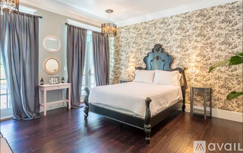 A bedroom with a large bed, a small table, and a chandelier.