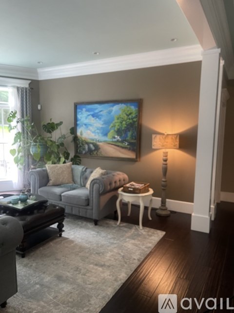 A living room with a grey couch, a coffee table, a lamp, and a painting on the wall.