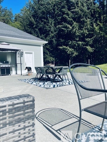 A patio with a black metal chair and a grey stone bench.
