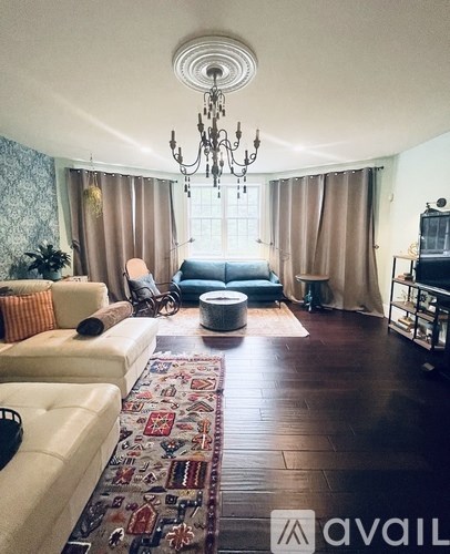 A living room with a chandelier, a couch, a chair, and a rug.