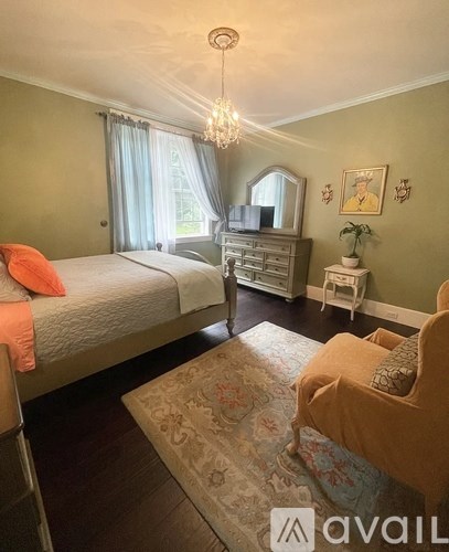 A bedroom with two beds, a dresser, and a chandelier.