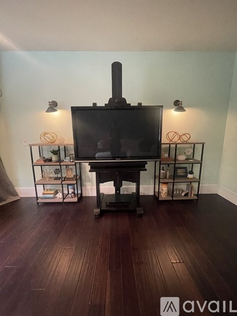 A black television set on a wooden stand with a white wall in the background.