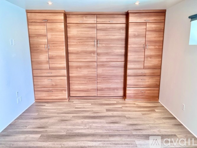 A room with wooden flooring and a wall of wooden cupboards.
