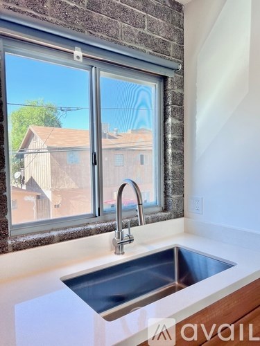 A kitchen sink with a window overlooking a residential area.