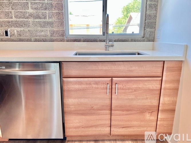 A kitchen with a stainless steel dishwasher and wooden cabinets.