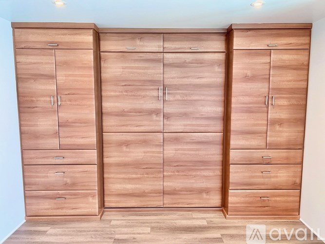 Three wooden wardrobes with drawers are in a room.