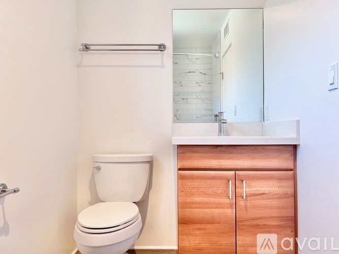 A white toilet sits next to a wooden cabinet in a bathroom.