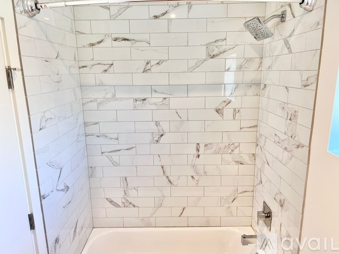 A shower with marble tiles and a glass door.