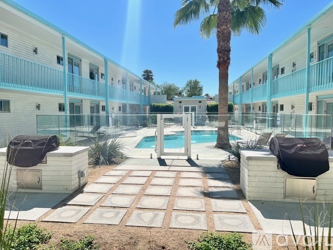 A pool surrounded by a tiled walkway and a palm tree.