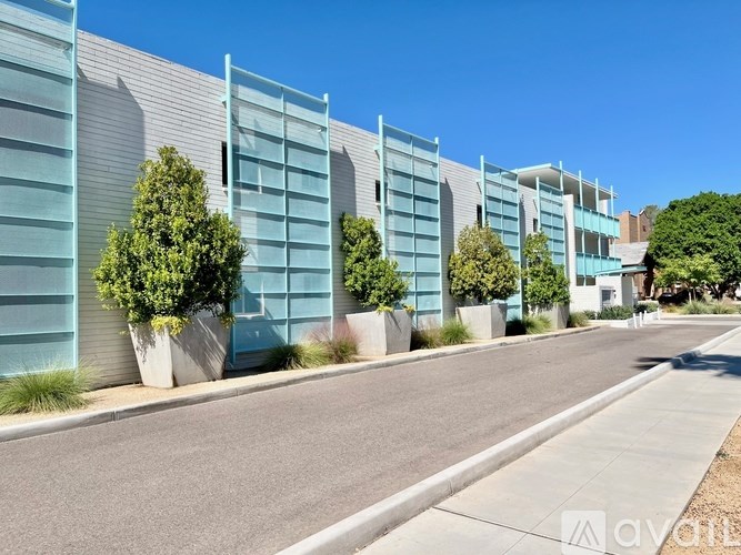 A row of modern buildings with blue and grey exterior and trees in front.