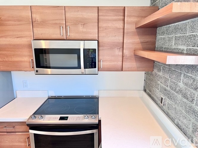 A kitchen with a stove, oven, microwave, and wooden cabinets.
