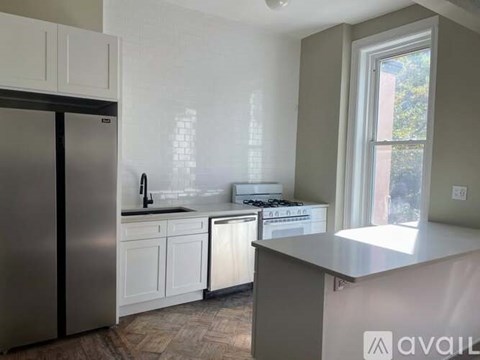 A kitchen with a stainless steel refrigerator and white cabinets.